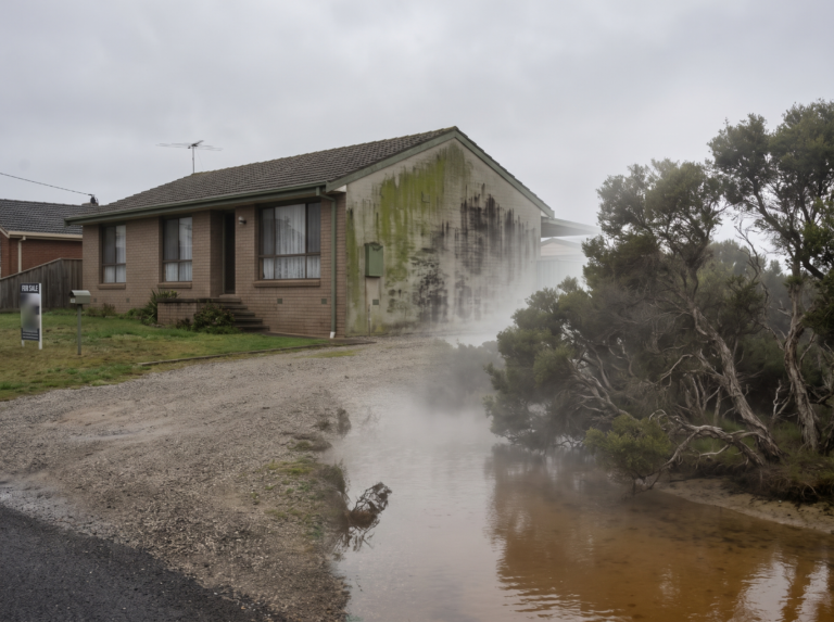 Rendered house near a Northern Beaches lagoon with mould staining on the shaded wall