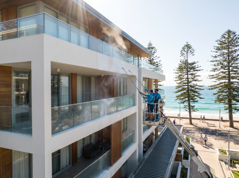 Manly beachside apartment building being soft washed with ocean behind