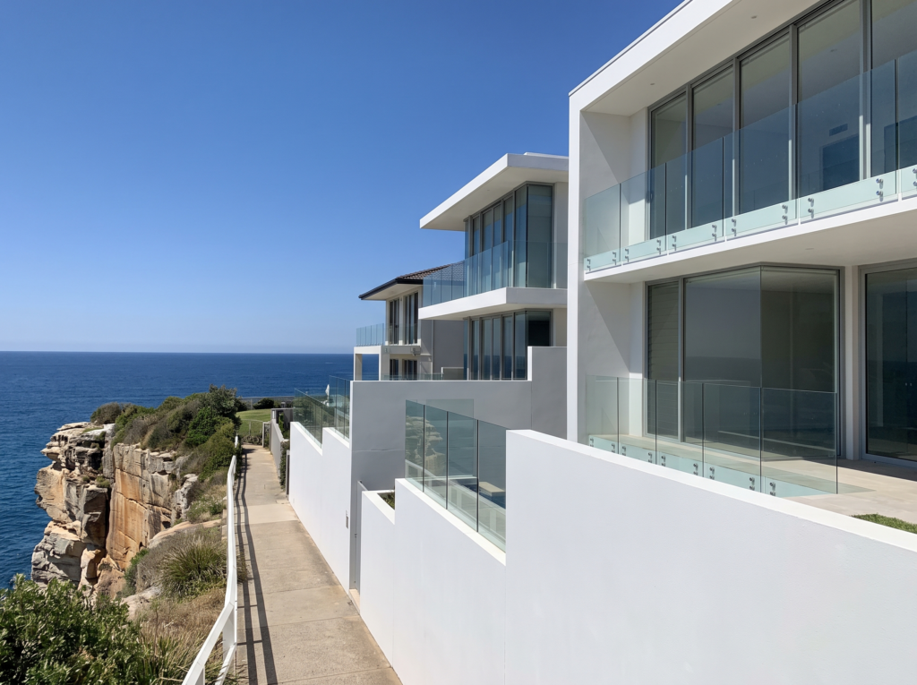 Modern clifftop homes in Dover Heights with clean glass balustrades above the ocean