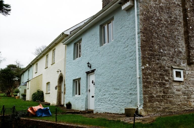 Rendered cottage walls showing weathering and shaded biological growth