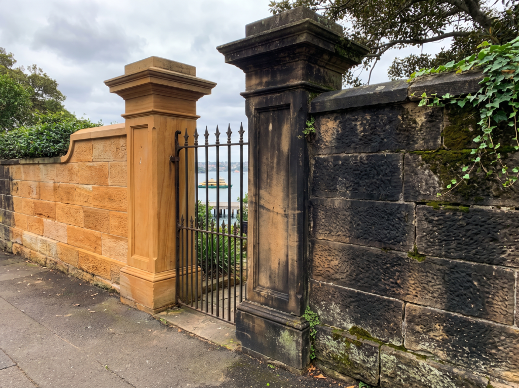 Victorian era sandstone boundary wall and gate posts in Darling Point, half restored