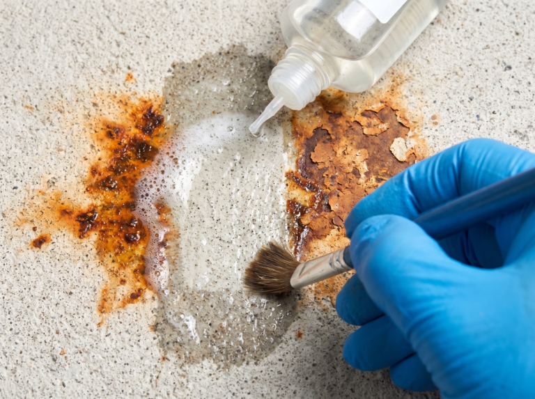 Orange rust stain on light concrete half dissolved by specialist treatment