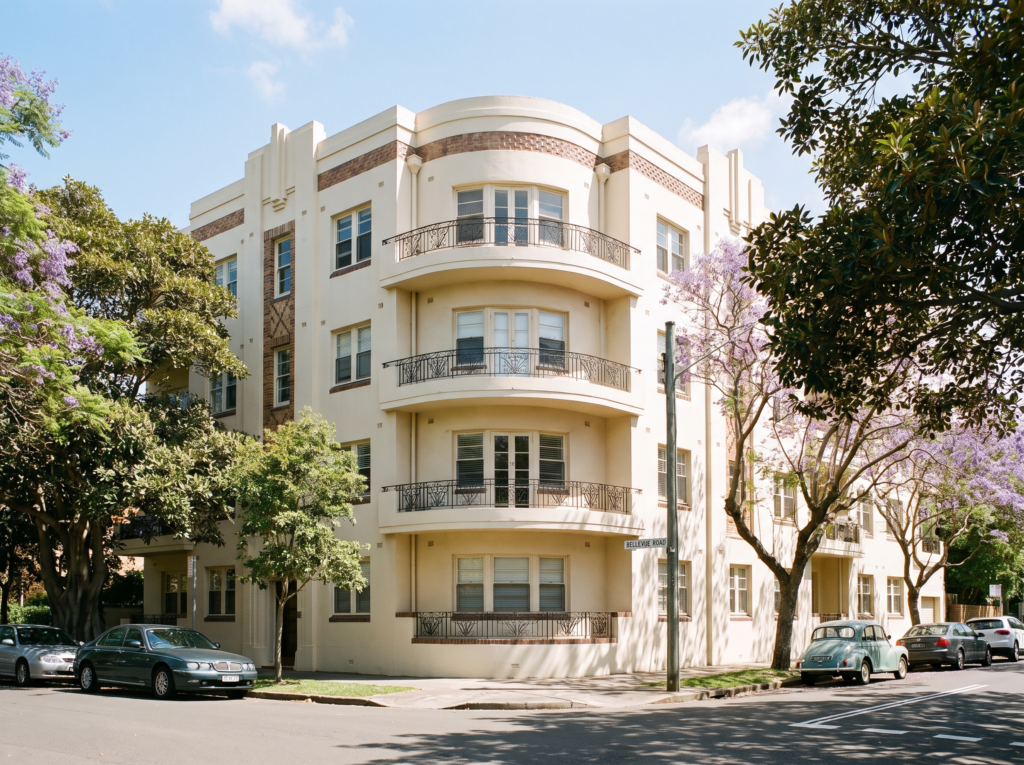 Interwar art deco apartment building with freshly washed cream render on a leafy Bellevue Hill street